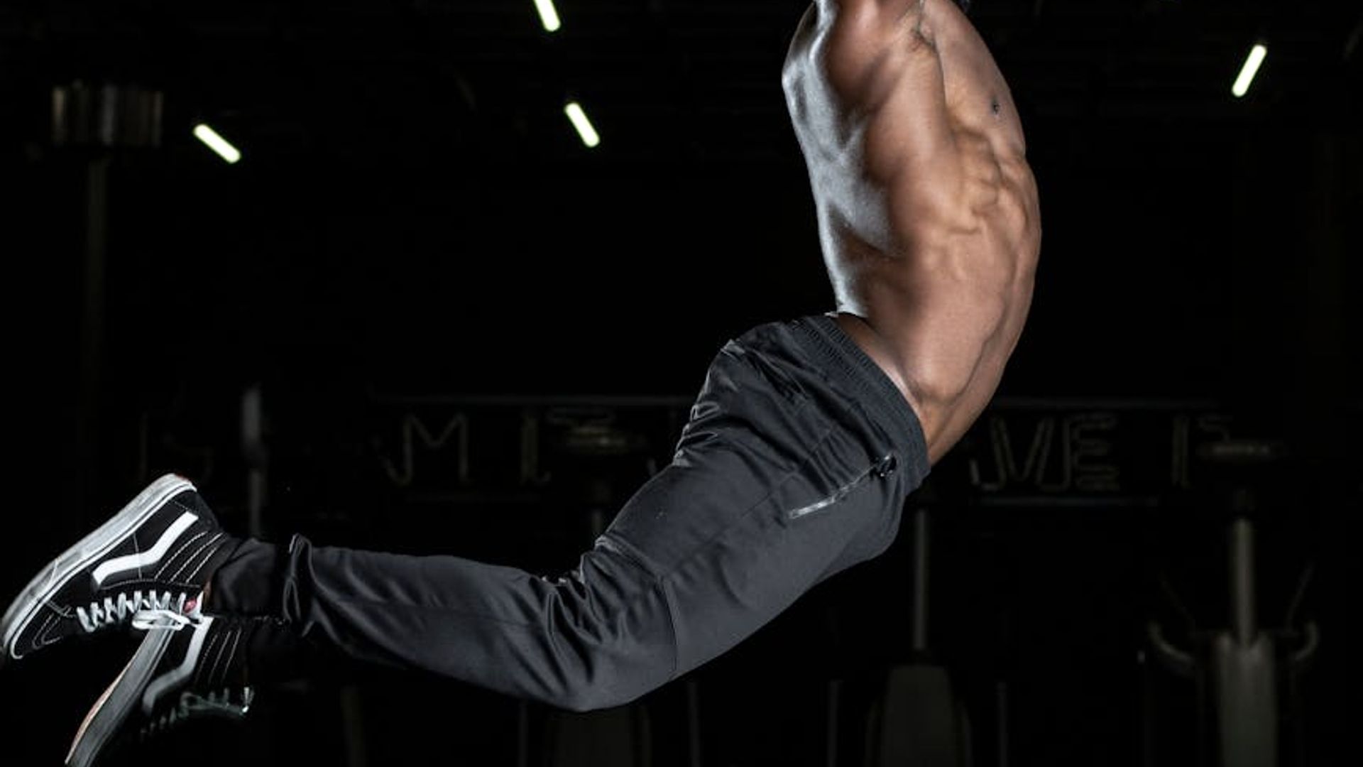 A person performing dynamic cardio movements in a dark studio